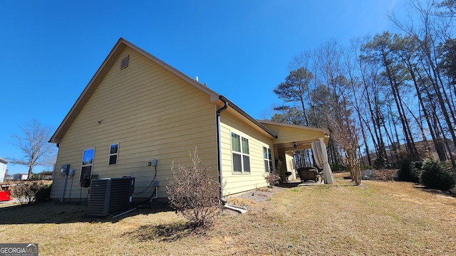 view of side of home featuring a yard and central AC unit