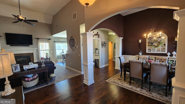 dining room with arched walkways, visible vents, wood finished floors, high vaulted ceiling, and ornate columns