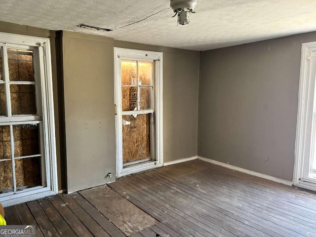 empty room featuring dark wood-style floors, baseboards, and visible vents