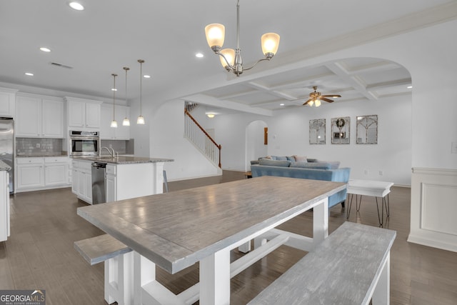 dining room featuring arched walkways, coffered ceiling, a ceiling fan, stairs, and beam ceiling