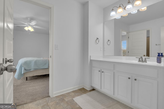 ensuite bathroom featuring stone finish flooring, connected bathroom, vanity, ceiling fan, and baseboards