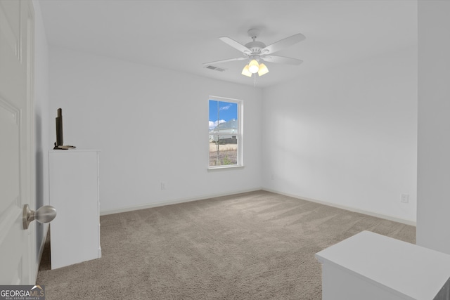 carpeted empty room with visible vents, ceiling fan, and baseboards