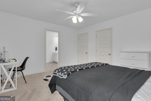 bedroom with light colored carpet, ceiling fan, ensuite bath, and baseboards