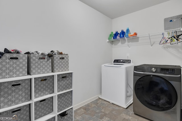 clothes washing area featuring laundry area, baseboards, stone finish floor, and independent washer and dryer