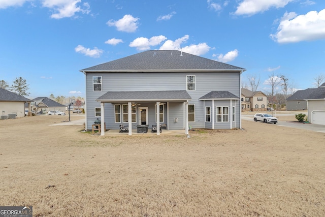 rear view of property featuring roof with shingles and a patio area