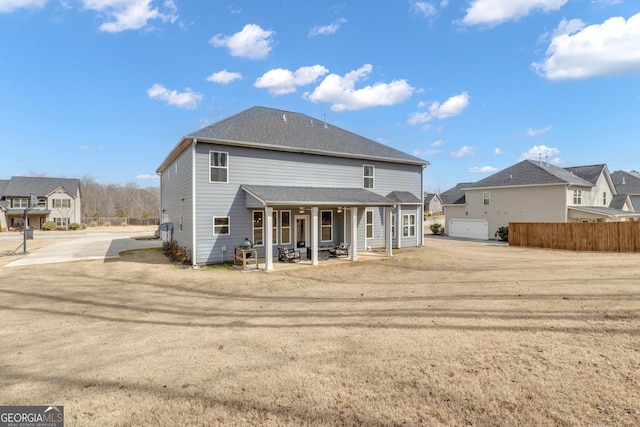 back of property featuring a shingled roof, fence, and a porch