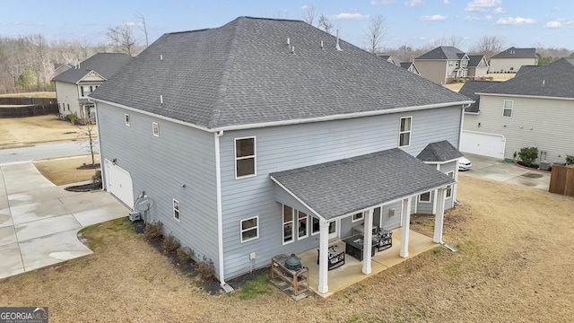 back of property featuring a shingled roof, a residential view, and a patio