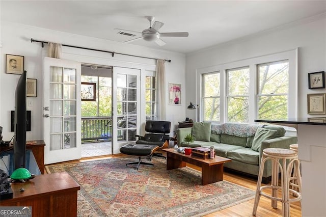 interior space with ornamental molding, visible vents, ceiling fan, and wood finished floors