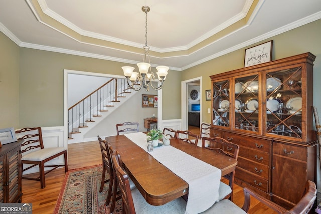 4740 Arbor Meadows Dr, Cumming, GA 30040 - dining space featuring a raised ceiling, wainscoting, wood finished floors, stairs, and a chandelier