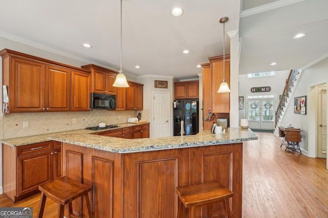 4740 Arbor Meadows Dr, Cumming, GA 30040 - kitchen featuring light stone counters, ornamental molding, brown cabinetry, light wood-style floors, and black appliances