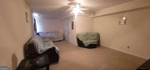 sitting room featuring a textured ceiling, carpet, a ceiling fan, and baseboards