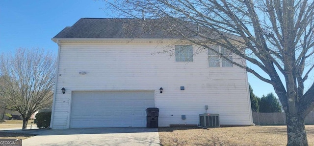 view of property exterior with concrete driveway, roof with shingles, fence, and central air condition unit