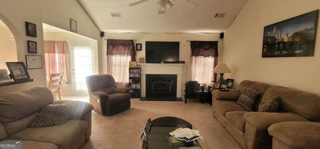 carpeted living area with vaulted ceiling, a fireplace, visible vents, and a ceiling fan