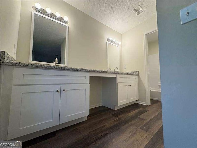 full bath with visible vents, wood finished floors, a textured ceiling, and vanity