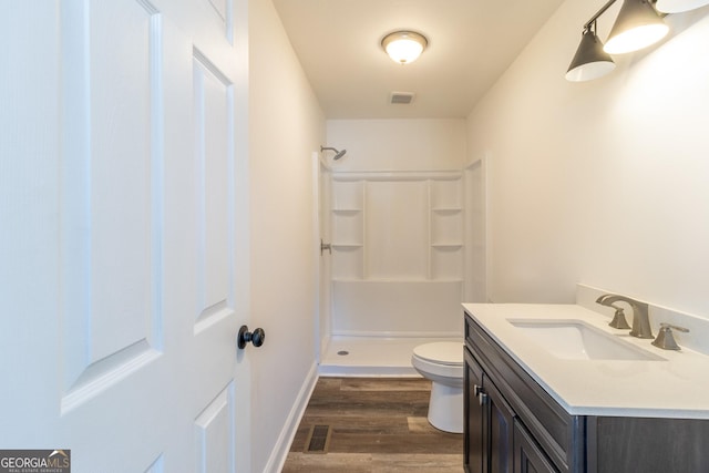 bathroom featuring vanity, a shower stall, toilet, and wood finished floors