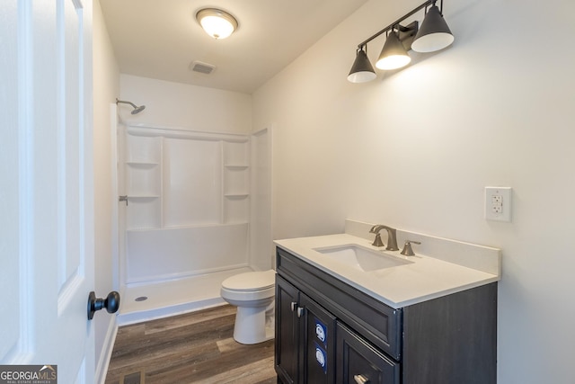 bathroom featuring a shower, visible vents, toilet, vanity, and wood finished floors