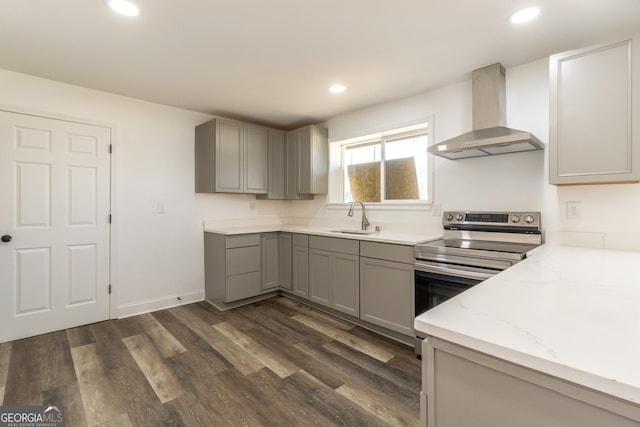 kitchen featuring gray cabinetry, a sink, stainless steel range with electric cooktop, wall chimney range hood, and dark wood finished floors