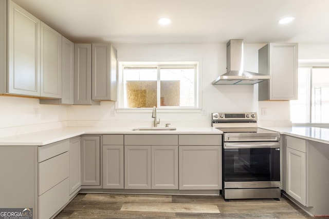 kitchen with recessed lighting, a sink, wood finished floors, stainless steel range with electric stovetop, and wall chimney exhaust hood