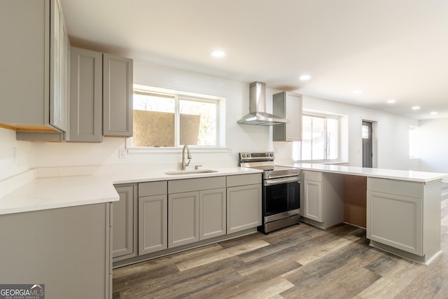 kitchen featuring gray cabinets, electric range, a sink, wall chimney range hood, and a peninsula