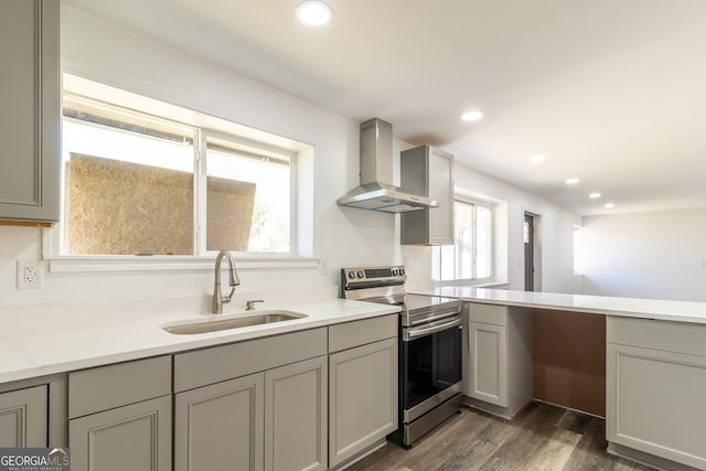 kitchen featuring gray cabinets, stainless steel range with electric cooktop, wall chimney range hood, a sink, and recessed lighting