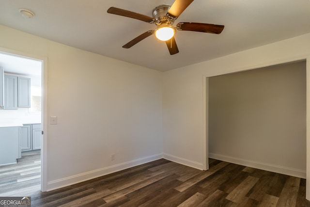 spare room featuring dark wood finished floors, baseboards, and ceiling fan