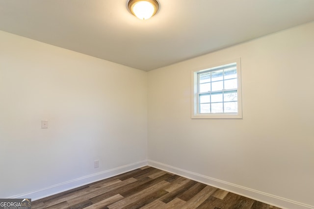 empty room with dark wood-style flooring and baseboards