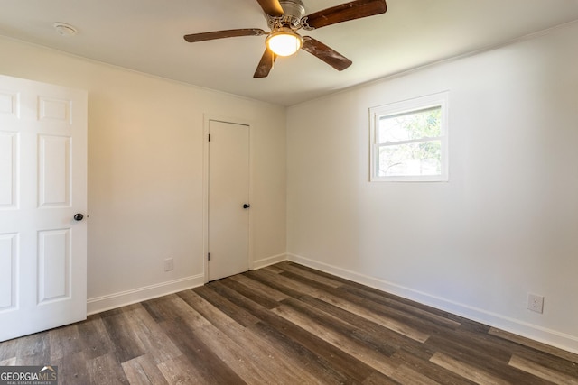 empty room featuring ceiling fan, baseboards, and dark wood finished floors