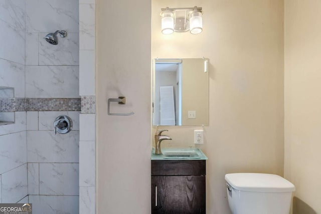 full bathroom featuring tiled shower, vanity, and toilet