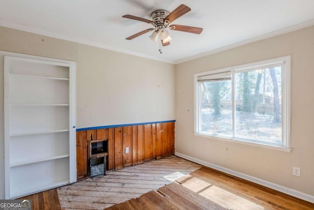 unfurnished living room with light wood finished floors, ceiling fan, baseboards, and crown molding