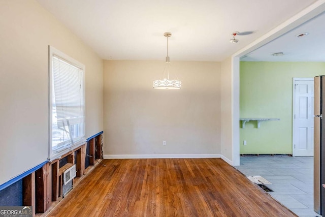 unfurnished dining area with baseboards and wood finished floors