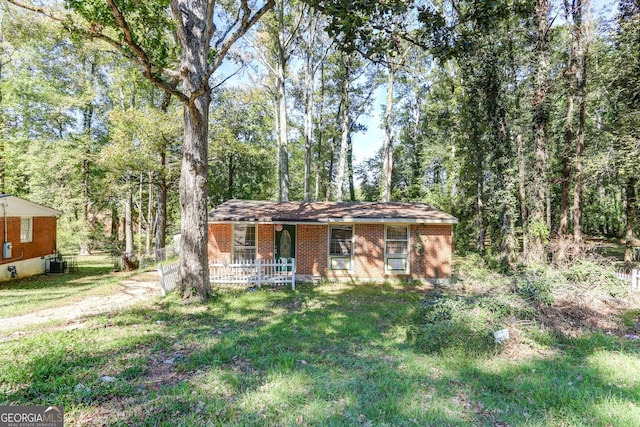 view of front of property with covered porch, central AC unit, a front lawn, and brick siding