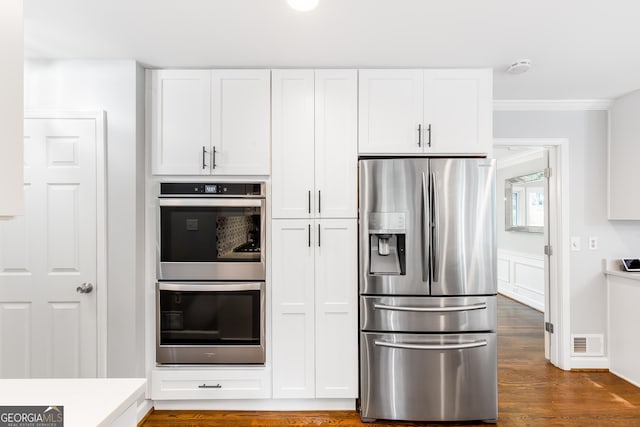 kitchen featuring visible vents, dark wood-style floors, stainless steel appliances, crown molding, and white cabinetry