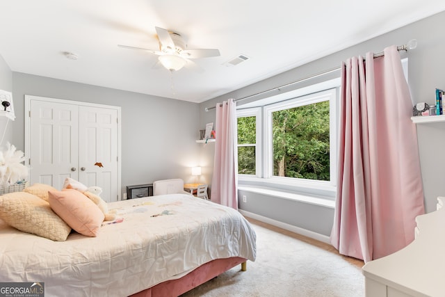 bedroom with a closet, visible vents, a ceiling fan, light carpet, and baseboards