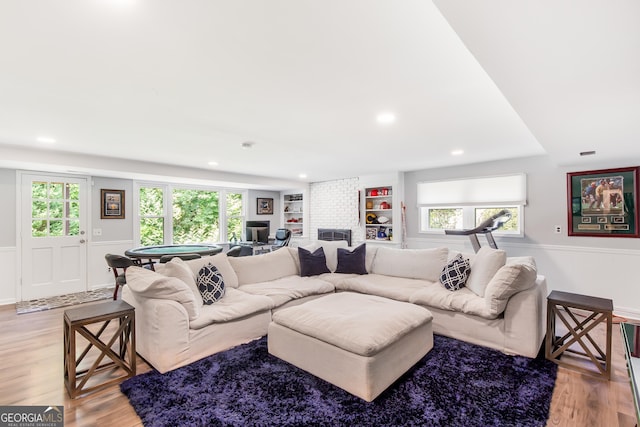 living area with built in features, a wealth of natural light, a wainscoted wall, and light wood finished floors