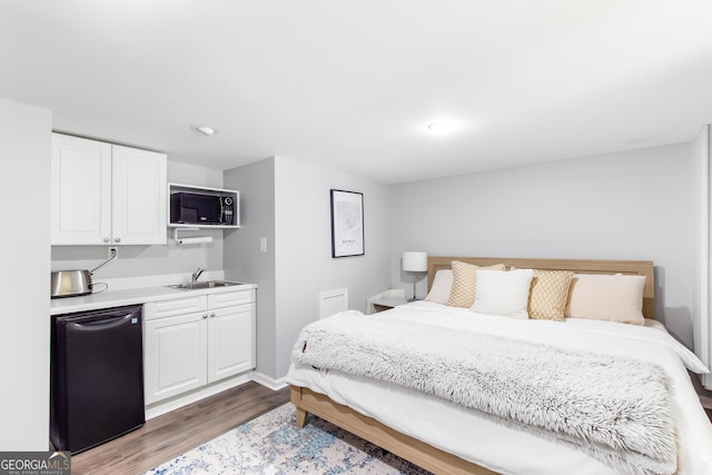 bedroom featuring baseboards, a sink, and wood finished floors