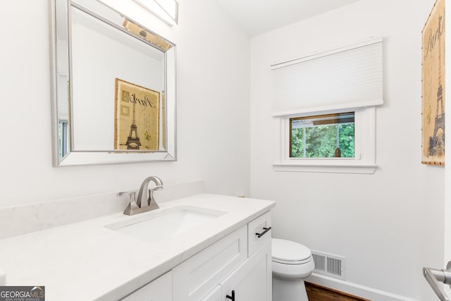 bathroom featuring toilet, baseboards, visible vents, and vanity