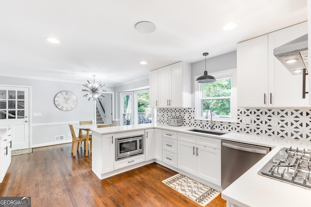 kitchen featuring visible vents, a peninsula, stainless steel appliances, light countertops, and a sink