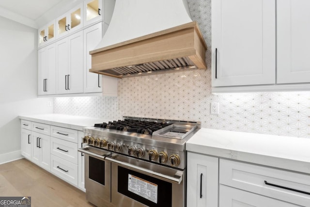 kitchen featuring white cabinets, custom range hood, glass insert cabinets, double oven range, and backsplash