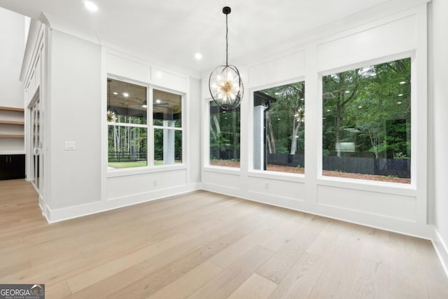 unfurnished dining area featuring a chandelier, light wood finished floors, recessed lighting, and a decorative wall