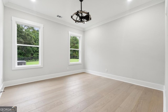 empty room with baseboards, ornamental molding, visible vents, and light wood-style floors