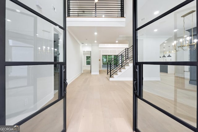 interior space with baseboards, wood finished floors, a high ceiling, stairs, and a notable chandelier