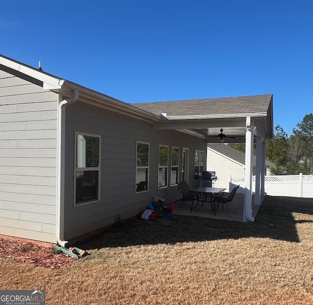 exterior space featuring fence, a yard, ceiling fan, a shingled roof, and a patio area