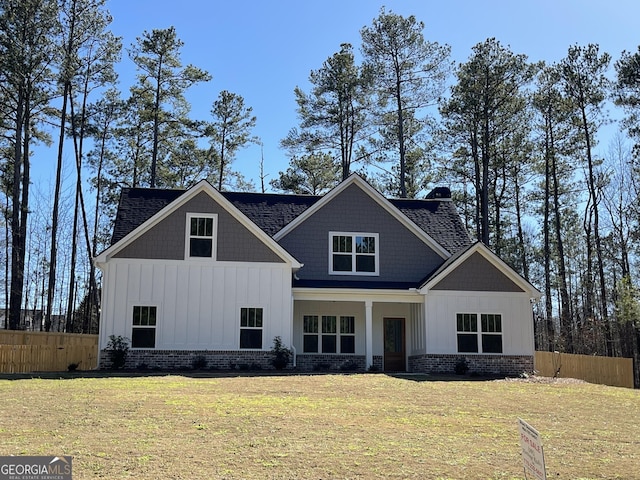 view of front of house featuring a front lawn, board and batten siding, a chimney, and fence