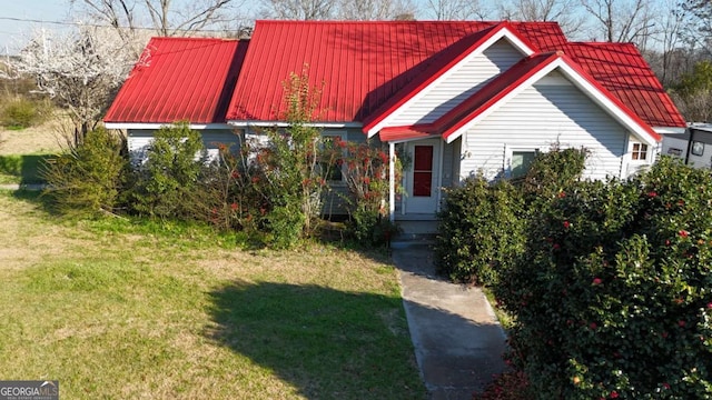 view of front facade with entry steps, a front lawn, and metal roof