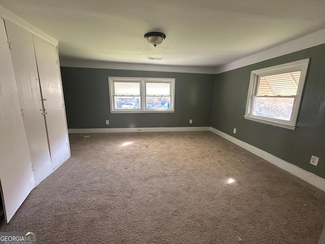 unfurnished bedroom featuring carpet, multiple windows, and baseboards