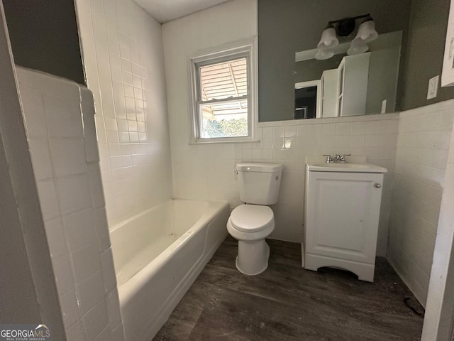 full bath featuring tile walls, toilet, vanity, wood finished floors, and a bath