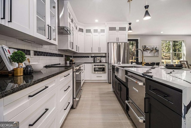 kitchen featuring a warming drawer, decorative backsplash, appliances with stainless steel finishes, white cabinets, and wall chimney range hood