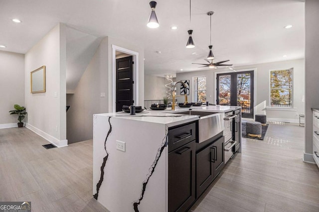 kitchen featuring an island with sink, light wood finished floors, recessed lighting, and decorative light fixtures