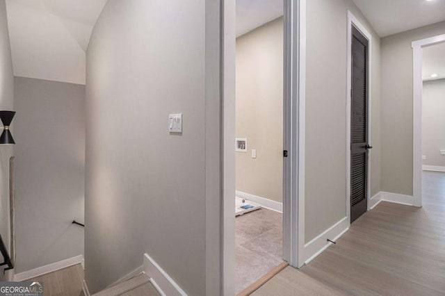 hallway with baseboards, wood finished floors, and an upstairs landing