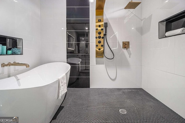 bathroom with a walk in shower, a freestanding bath, and tile walls